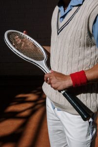 Photo of a Person with a Red Wristband Holding a Black and White Tennis Racket
